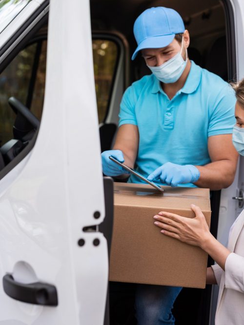 Prevention masks are new safety measures. Young woman receiving package from the delivery man on a van